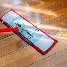 Mop z czerwoną rączką czyści drewniane panele. Dowiedz się, czym myć panele, by lśniły czystością.