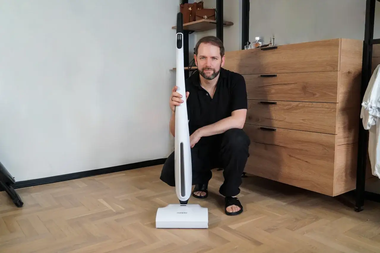 Mężczyzna prezentuje nowoczesny mop bioniczny, który może znaleźć się na szczycie rankingu najlepszych urządzeń do sprzątania.
